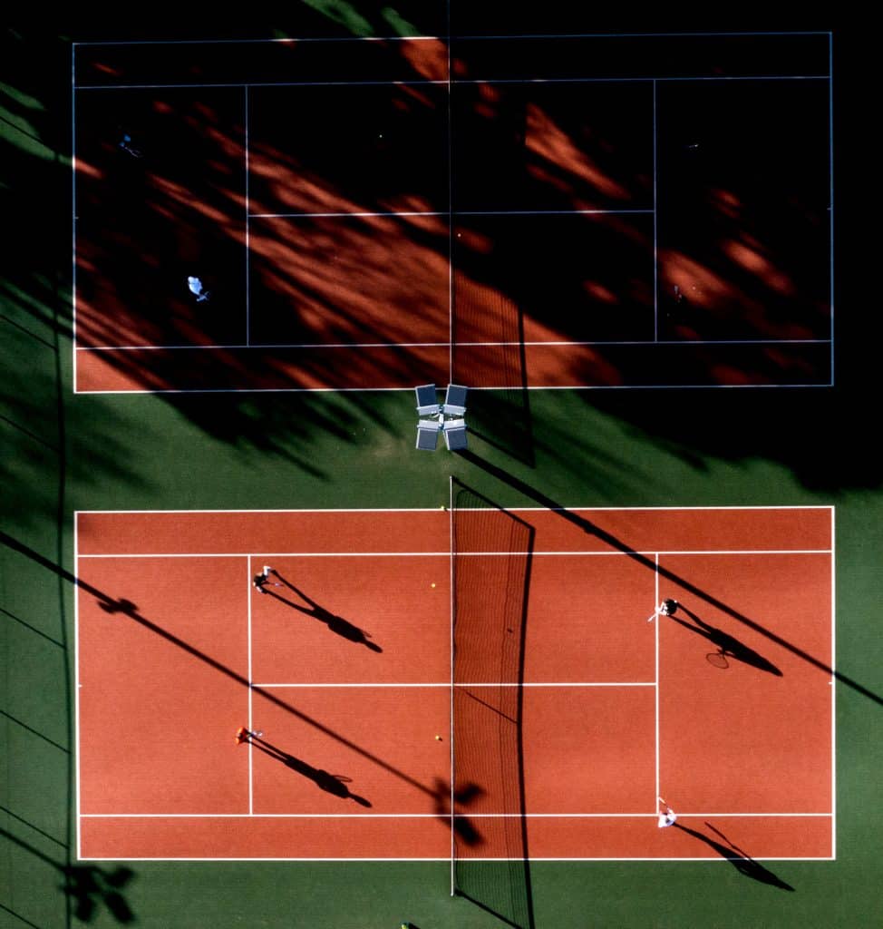 Two tennis courts with shadows on the court