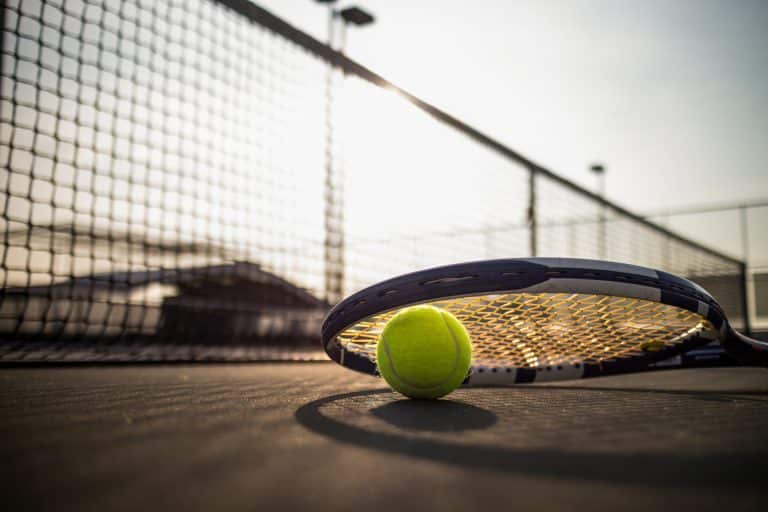 Tennis ball and racket lying on tennis court