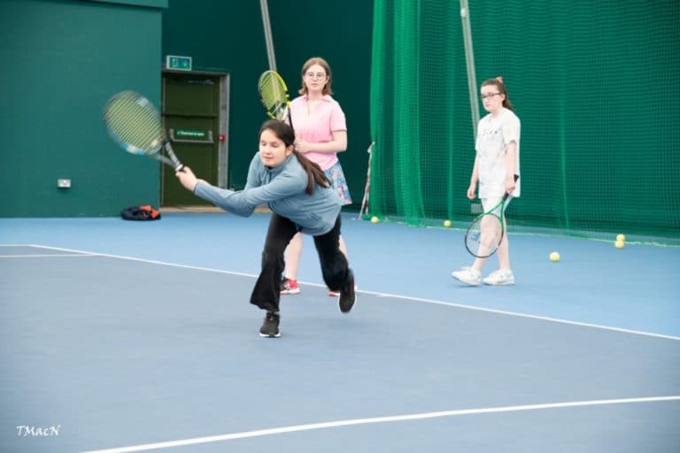 Girl reaching for tennis ball with racket