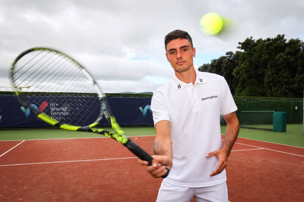 Male tennis player wearing white hitting a tennis ball